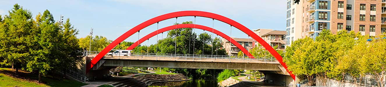 red bridge over a river with green parkway on either side